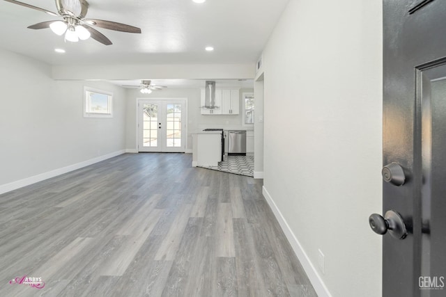 unfurnished living room with light wood-type flooring, ceiling fan, and french doors