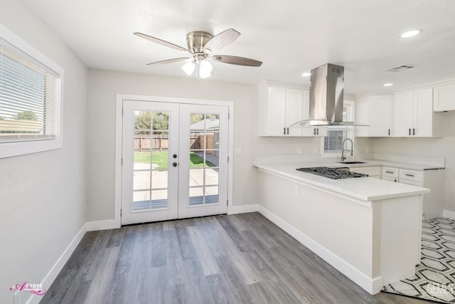 kitchen with white cabinetry, island range hood, kitchen peninsula, gas cooktop, and french doors