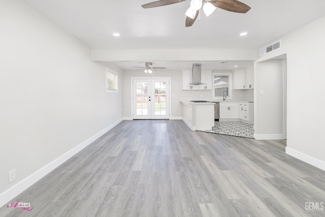 unfurnished living room featuring ceiling fan, sink, french doors, and light wood-type flooring