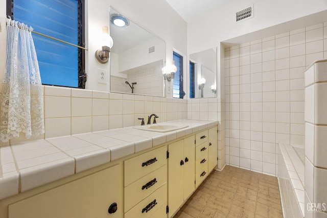 bathroom with decorative backsplash, vanity, and tile walls