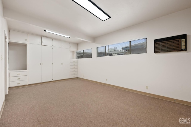 unfurnished bedroom featuring light colored carpet, an AC wall unit, and a closet