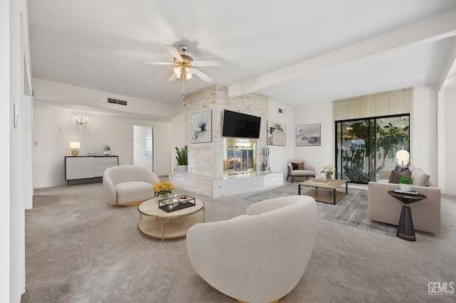 living room featuring beamed ceiling, ceiling fan, a large fireplace, and light colored carpet