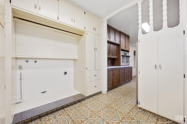 kitchen featuring wall oven and dark brown cabinetry