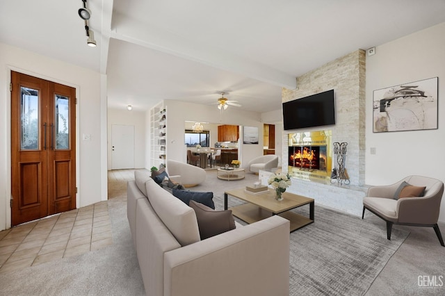 carpeted living room featuring ceiling fan, a fireplace, and beamed ceiling