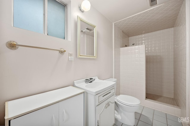 bathroom with tile patterned floors, toilet, vanity, and tiled shower