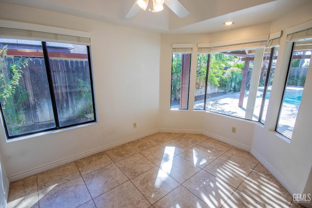 tiled empty room with ceiling fan and baseboards