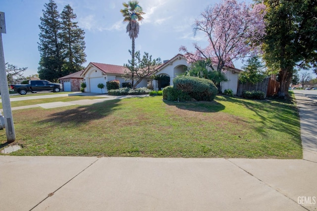 view of front of property with stucco siding, an attached garage, concrete driveway, and a front yard