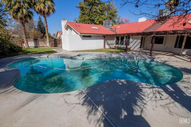 view of pool with a patio, central AC, a fenced backyard, and a pool with connected hot tub