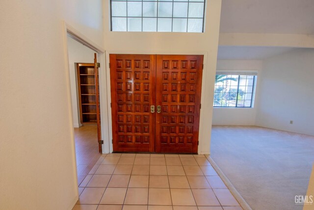 entrance foyer with a high ceiling, light tile patterned floors, and light carpet