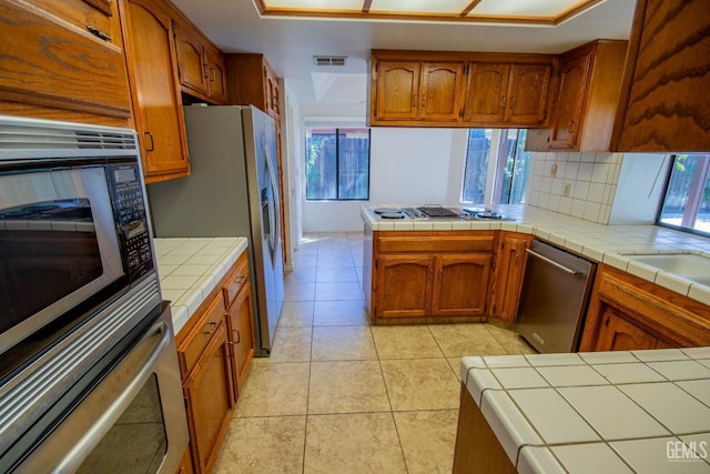 kitchen featuring visible vents, appliances with stainless steel finishes, and brown cabinetry