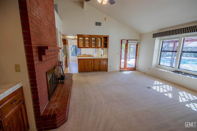 unfurnished living room featuring a fireplace, a ceiling fan, a wealth of natural light, and light carpet