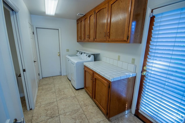 washroom featuring washer and dryer, visible vents, cabinet space, and light tile patterned floors