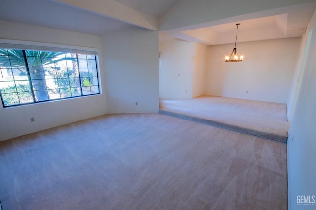 spare room with a tray ceiling, carpet floors, and an inviting chandelier