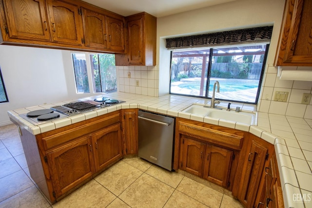 kitchen with a wealth of natural light, decorative backsplash, stainless steel dishwasher, and a sink