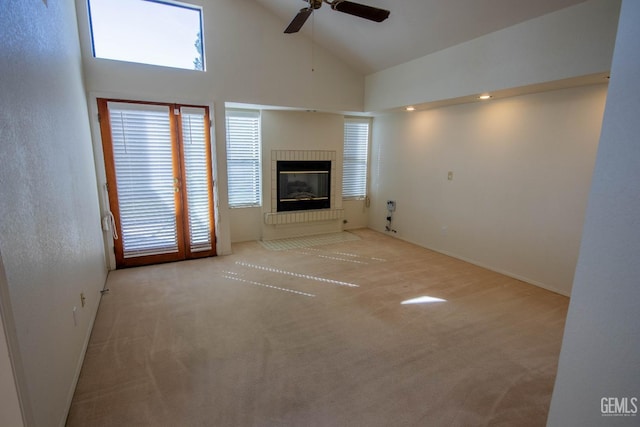 unfurnished living room featuring plenty of natural light, high vaulted ceiling, carpet floors, and a ceiling fan