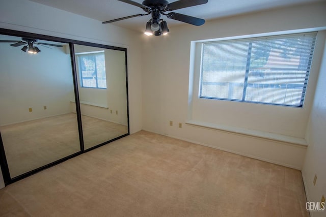 unfurnished bedroom with ceiling fan, a closet, and light carpet