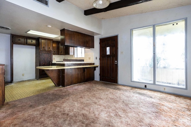 kitchen with decorative backsplash, plenty of natural light, kitchen peninsula, and light carpet