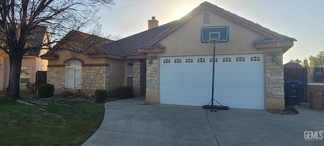 view of front of property with concrete driveway, stone siding, an attached garage, and stucco siding