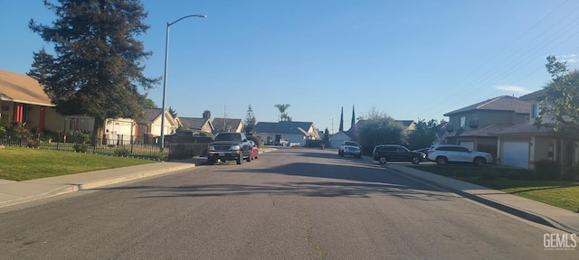 view of street with sidewalks, a residential view, curbs, and street lights