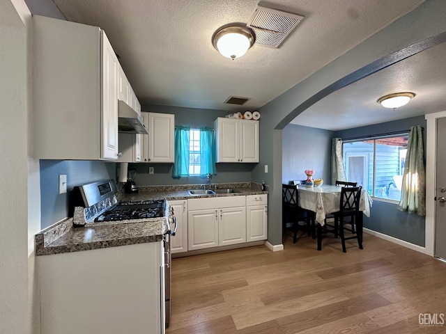 kitchen featuring sink, light hardwood / wood-style floors, a textured ceiling, white cabinets, and stainless steel range with gas cooktop