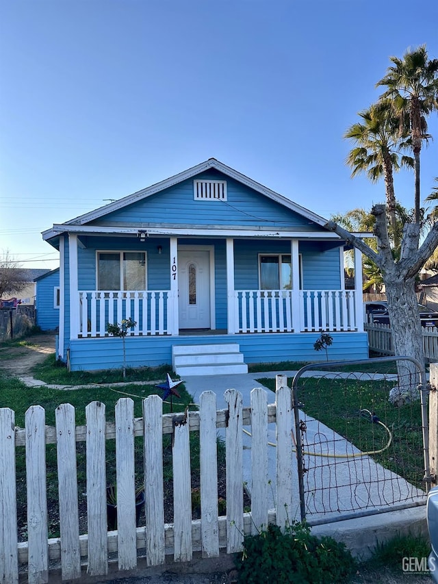 bungalow with covered porch and a front lawn