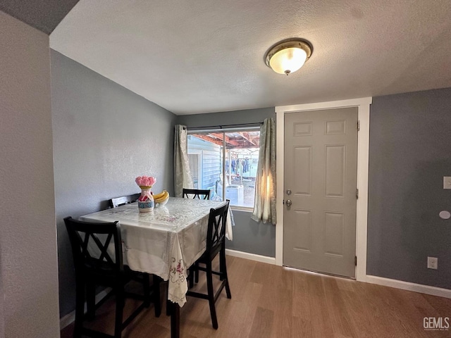 dining room with hardwood / wood-style floors and a textured ceiling