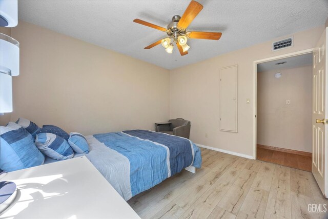 9408 Wandering Oak Dr, Bakersfield, CA 93311 - bedroom featuring light wood-type flooring, baseboards, a ceiling fan, a wall mounted AC, and a textured ceiling