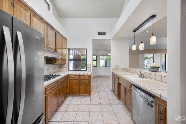 9408 Wandering Oak Dr, Bakersfield, CA 93311 - kitchen featuring stainless steel appliances, tile counters, a sink, backsplash, and under cabinet range hood