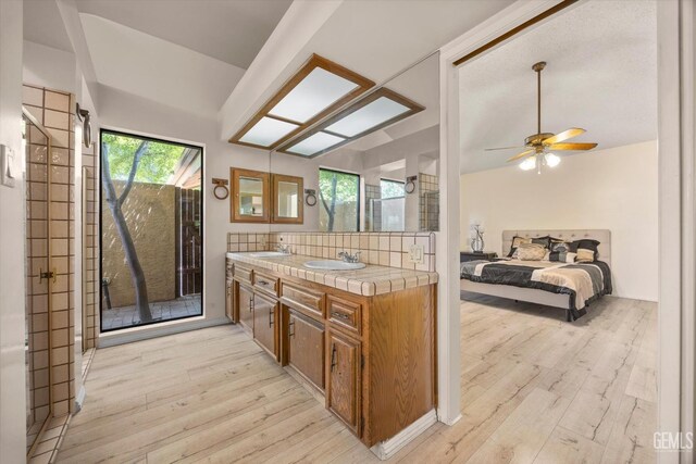 9408 Wandering Oak Dr, Bakersfield, CA 93311 - kitchen featuring tile counters, light wood-style floors, a sink, brown cabinets, and lofted ceiling