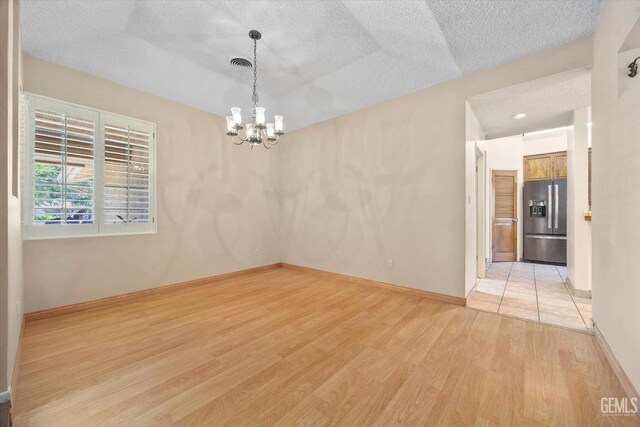 9408 Wandering Oak Dr, Bakersfield, CA 93311 - spare room featuring light wood-style floors, a textured ceiling, a chandelier, and baseboards