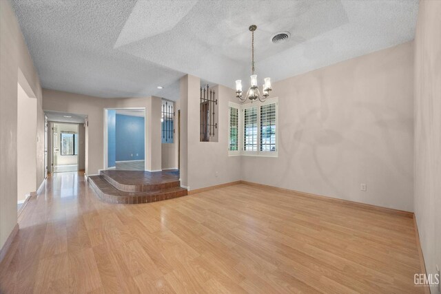 9408 Wandering Oak Dr, Bakersfield, CA 93311 - unfurnished room featuring wood finished floors, a chandelier, a textured ceiling, and baseboards