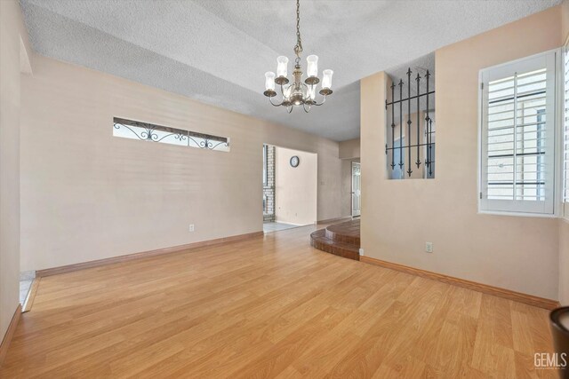9408 Wandering Oak Dr, Bakersfield, CA 93311 - empty room with a chandelier, wood finished floors, baseboards, and a textured ceiling