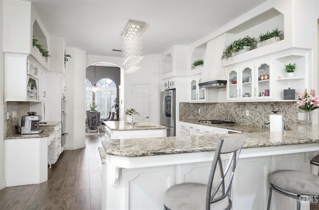 10505 Finchley Dr, Bakersfield, CA 93311 - kitchen with arched walkways, a peninsula, open shelves, stainless steel appliances, and a kitchen island with sink