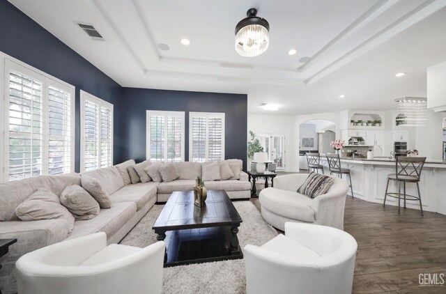 10505 Finchley Dr, Bakersfield, CA 93311 - living area featuring arched walkways, dark wood finished floors, a tray ceiling, recessed lighting, and a chandelier