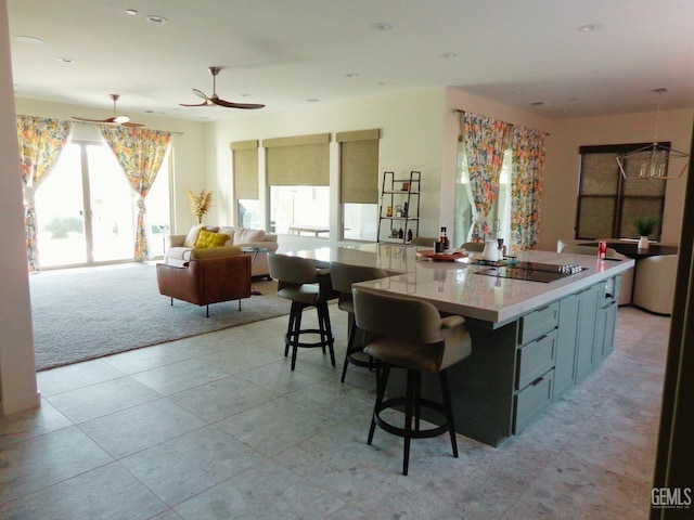 kitchen featuring light tile patterned floors, ceiling fan, open floor plan, black electric stovetop, and light countertops