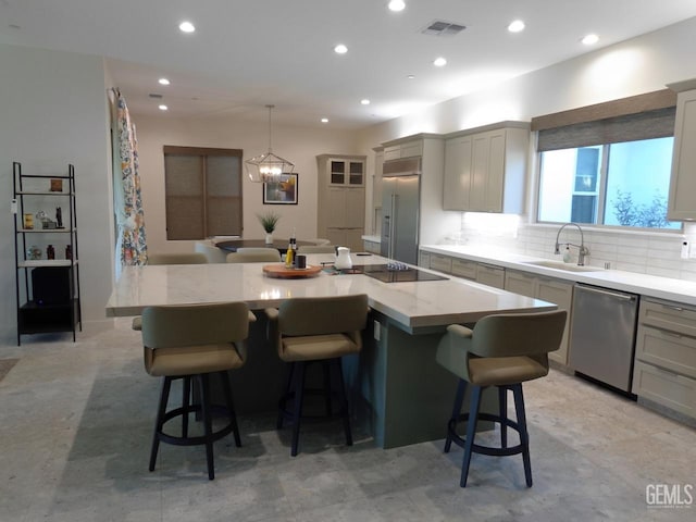 kitchen featuring visible vents, decorative backsplash, a large island, stainless steel appliances, and a sink