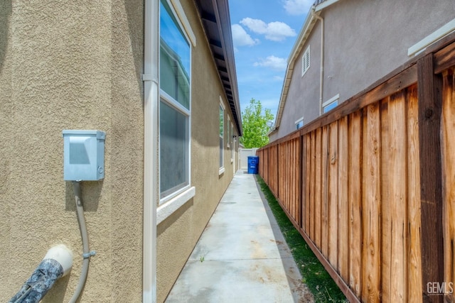 view of side of home with stucco siding and fence