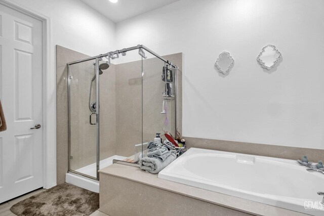 full bathroom with a shower stall and a bath