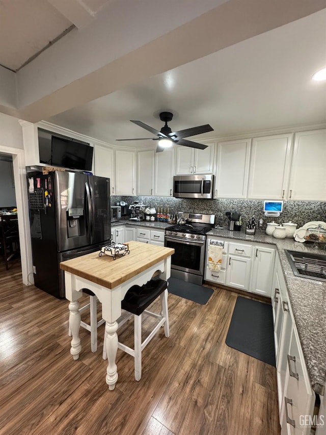 kitchen featuring dark wood-style floors, a sink, decorative backsplash, white cabinetry, and appliances with stainless steel finishes