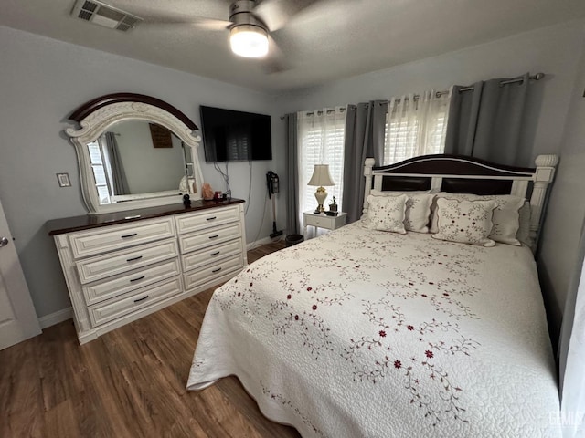 bedroom with a ceiling fan, visible vents, baseboards, and dark wood-type flooring