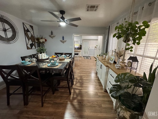 dining room with dark wood-style flooring, visible vents, and a ceiling fan
