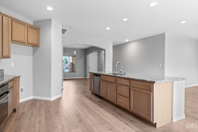 6522 Bangor Pl, Bakersfield, CA 93313 - kitchen with arched walkways, appliances with stainless steel finishes, a center island with sink, light stone counters, and light wood-style flooring