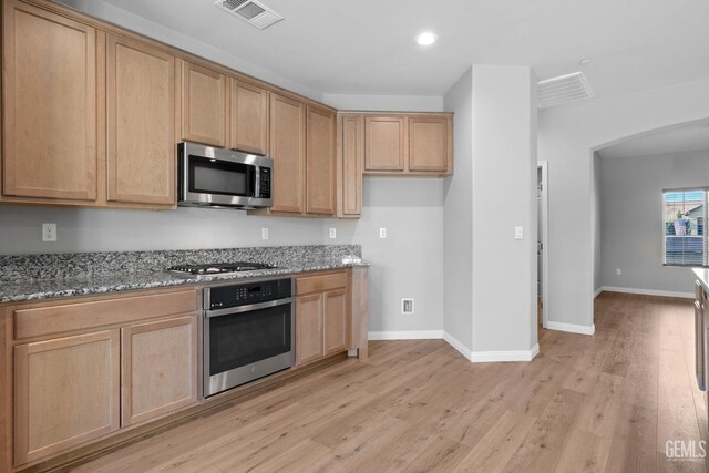 6522 Bangor Pl, Bakersfield, CA 93313 - kitchen featuring appliances with stainless steel finishes, light stone countertops, light wood-style floors, arched walkways, and recessed lighting