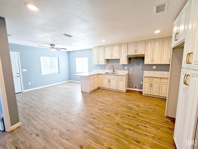 kitchen featuring ceiling fan, sink, refrigerator, a textured ceiling, and light wood-type flooring