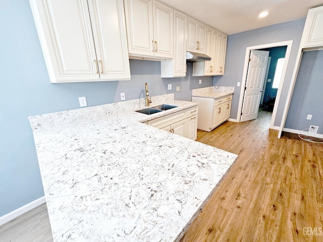 kitchen featuring sink, white cabinets, and light hardwood / wood-style flooring