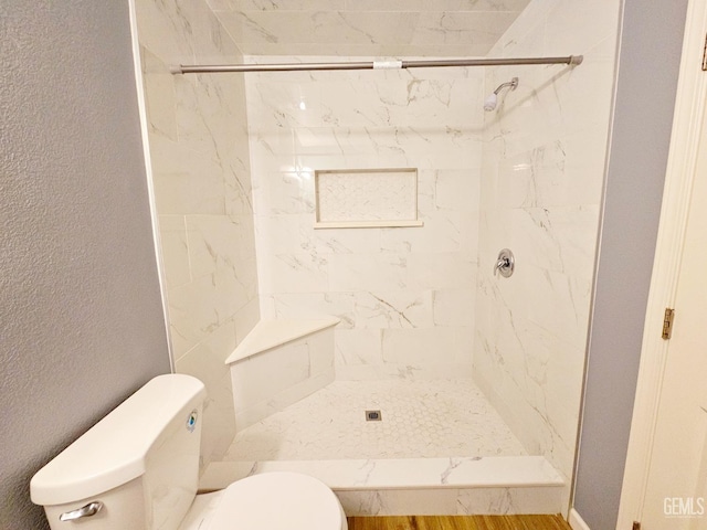 bathroom featuring a tile shower and toilet