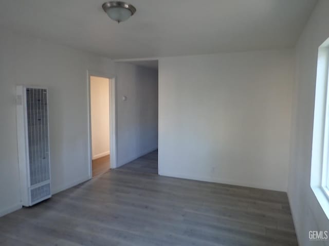 spare room featuring a heating unit and wood finished floors