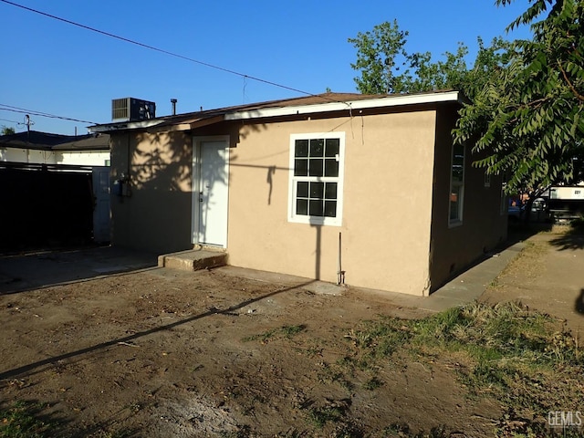 view of property exterior featuring central air condition unit, stucco siding, and fence