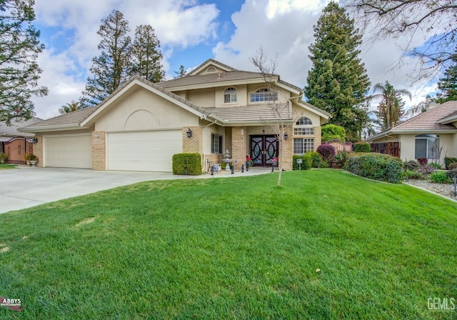 traditional home featuring stucco siding, driveway, a front lawn, an attached garage, and brick siding