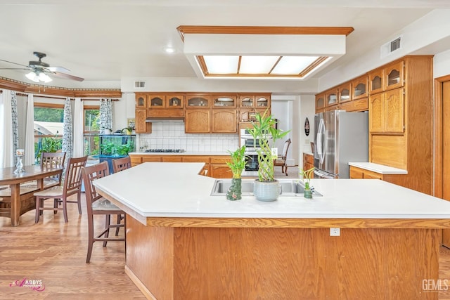 kitchen with brown cabinets, stainless steel appliances, light countertops, and a sink